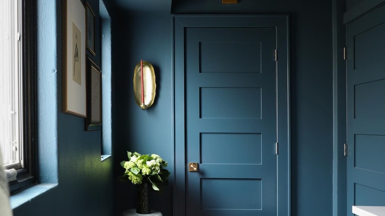 A small bathroom with blue-colored ceiling, walls, and doors