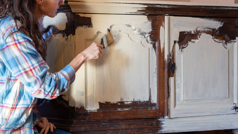 Woman painting a brown cabinet off-white