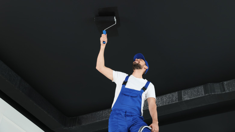 Man painting ceiling black