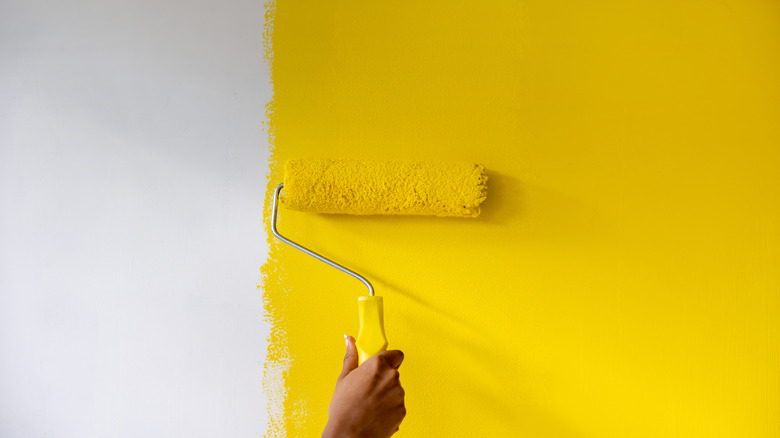 Hand painting white wall yellow with a roller