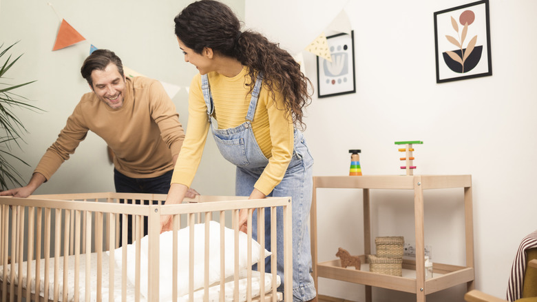 Parents installing crib in nursery