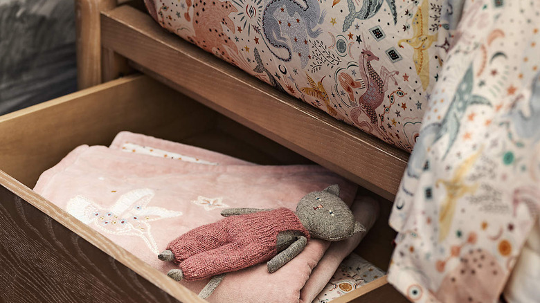 Stuffed animals and blanket in drawers under whimsical children's comforter