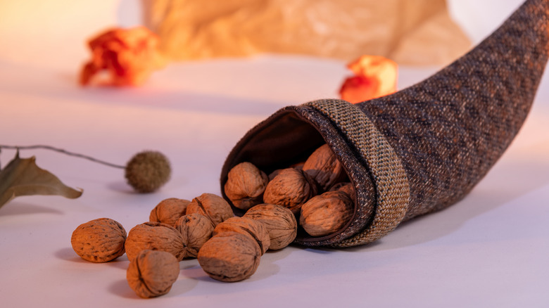 A small fabric cornucopia on the table with walnuts escaping