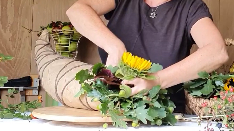 A woman filling a cornucopia made from brown paper and rope