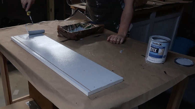 person rolling primer on furniture
