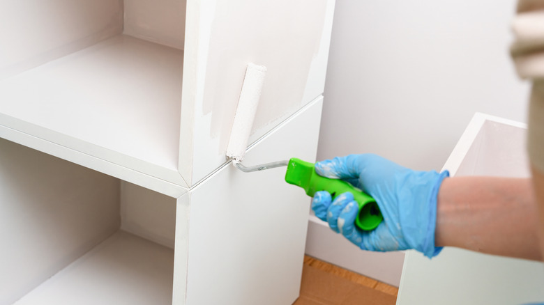 hand rolling paint onto furniture