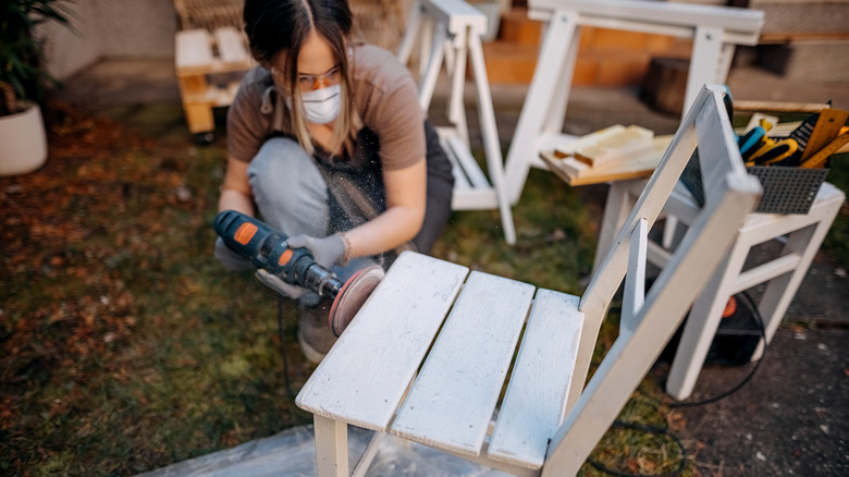 person sanding painted chair
