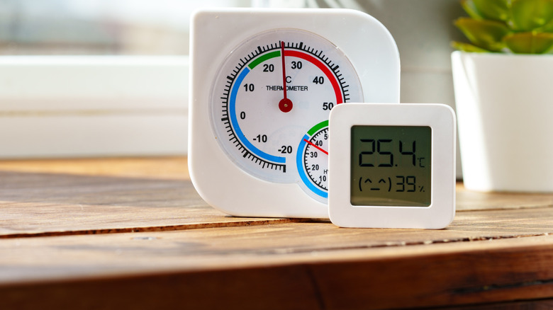 Digital thermometer displaying temperature and humidity near window