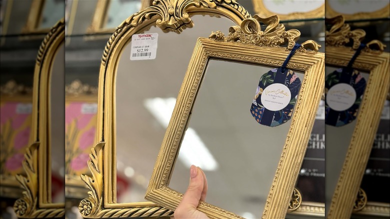 person holding gold frames in store