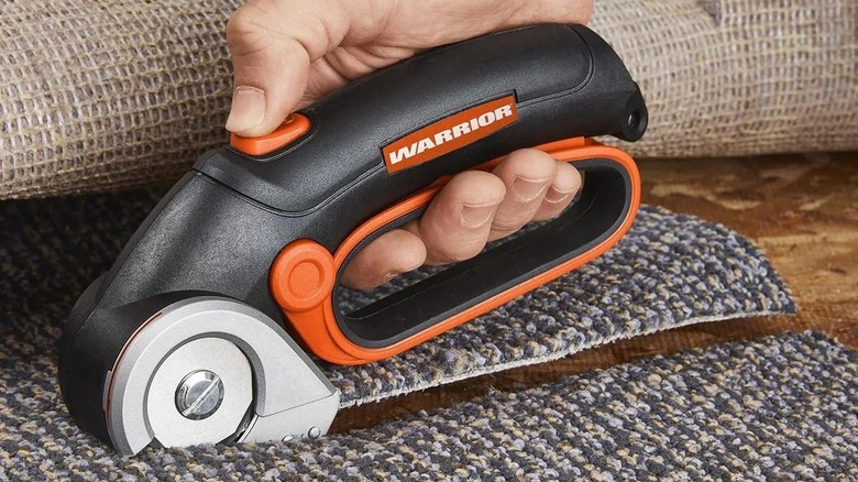 Person cutting carpet with a power tool