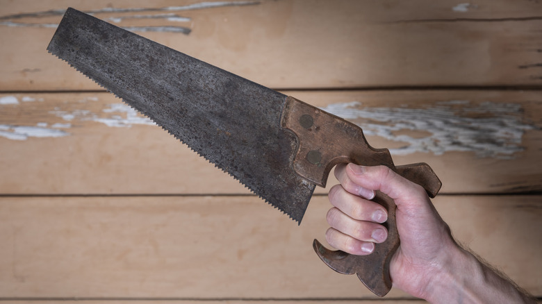 vintage hand saw in person's hand