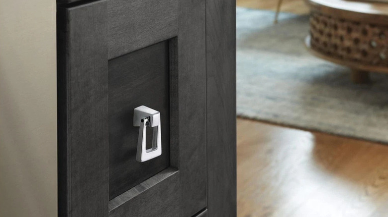 A close-up of brown cabinets with a silver triangle handle pull.