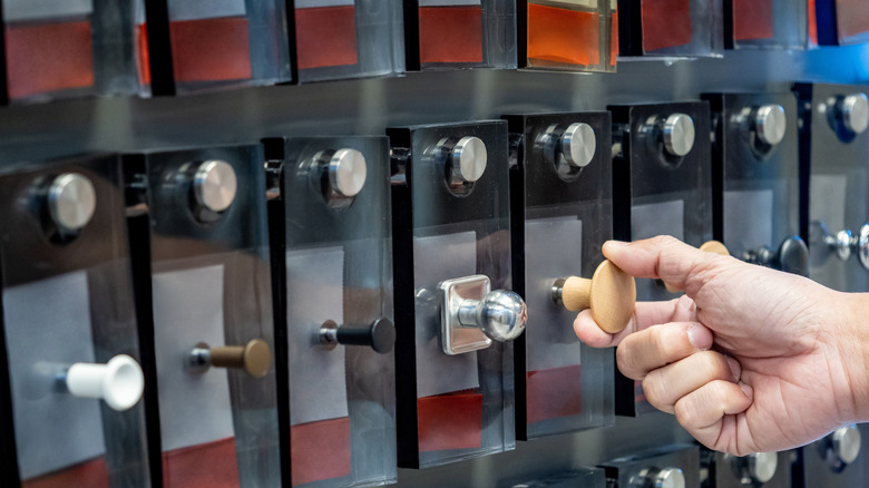 A person shopping for cabinet knobs from an assorted display.