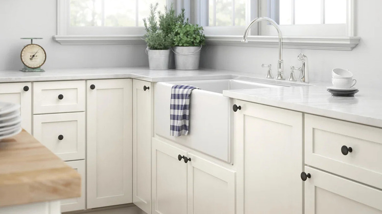 A close-up of white kitchen cabinets with brown metal knobs.