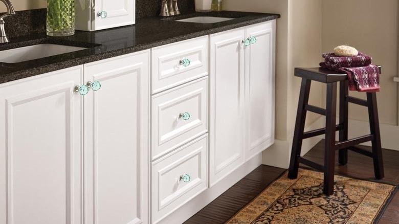 A close-up of white cabinets with blue crystal knobs.
