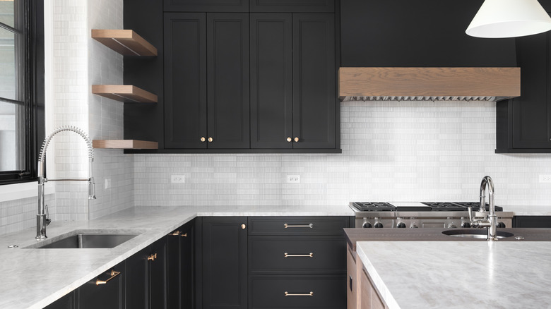 A black and white kitchen with wood shelves.
