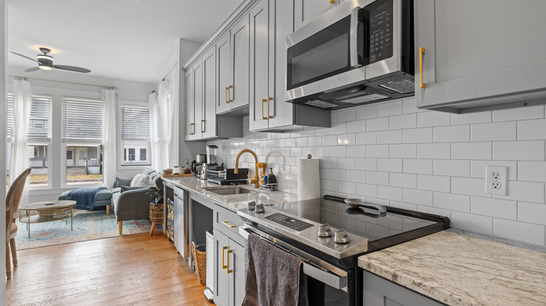 A gray kitchen with stone counters and gold fixtures.