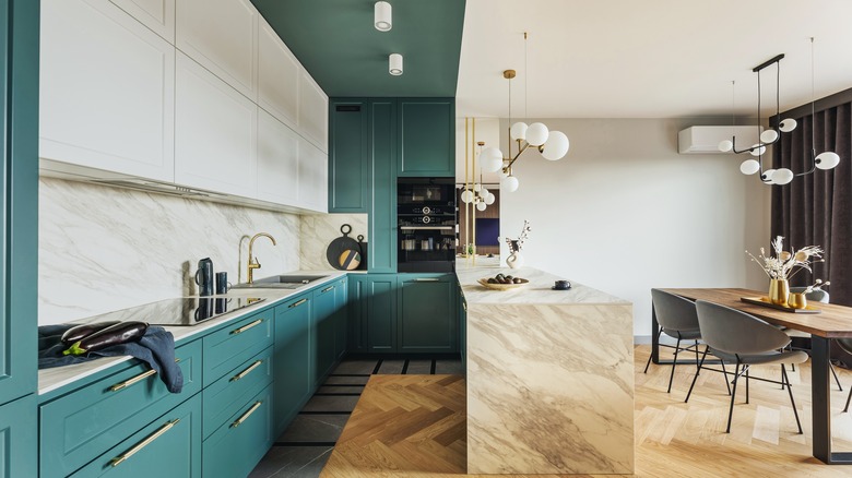 A turquoise kitchen with natural stone counters and backsplash.