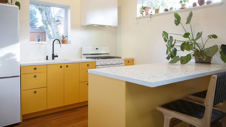A small yellow kitchen with speckled stone counters.