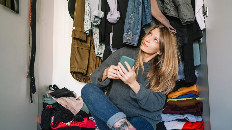Overwhelmed woman sitting on the floor of her closet