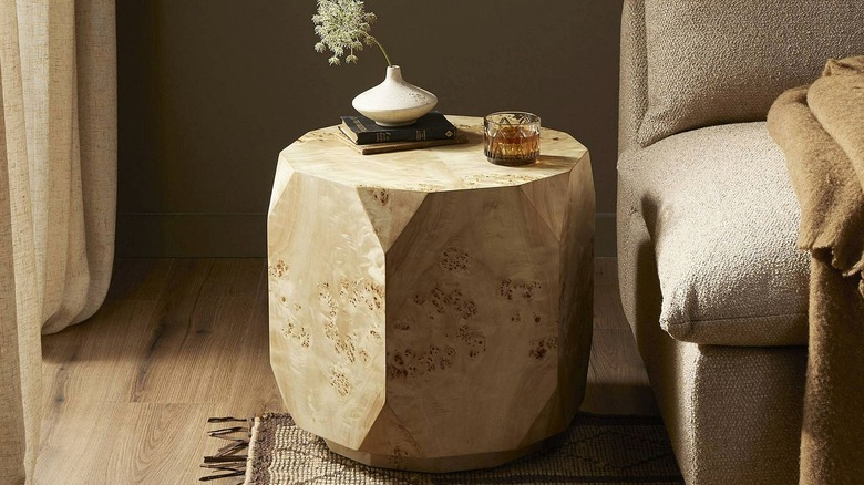 A solid side table with a poplar burl veneer, sitting next to a sofa