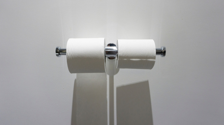 wall mounted bracket holding two rolls of toilet paper