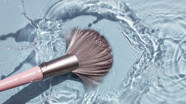 Makeup brush with pink handle in water