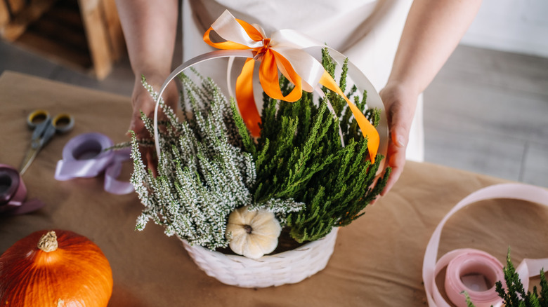 A handled basket is filled half with white speedwell and half with greenery.