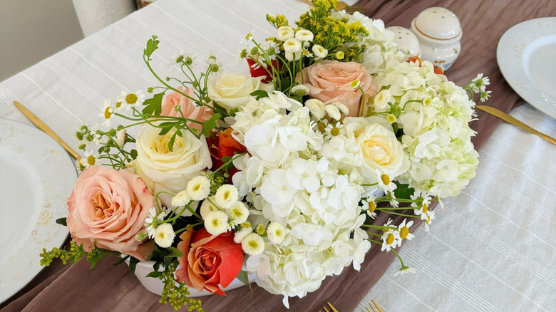 A casserole dish holds a centerpiece of flowers.
