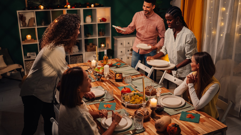 A group of friends and family sit down to a Thanksgiving dinner.