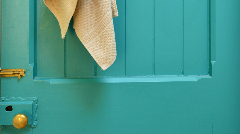 A bright teal bathroom door with a towel.