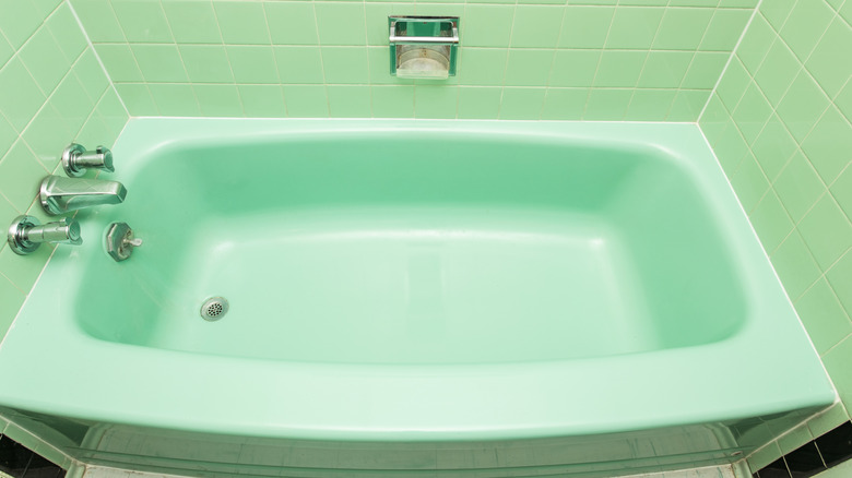 A mint green bathtub with matching tile.