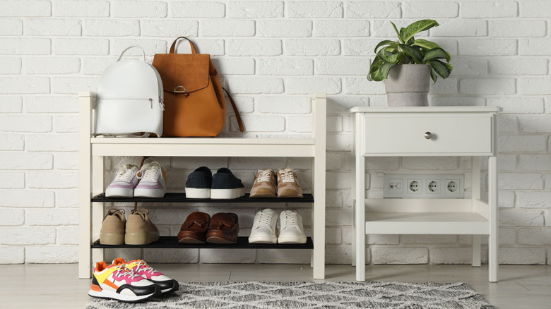 A white shoe storage bench next to a side table in an entryway.
