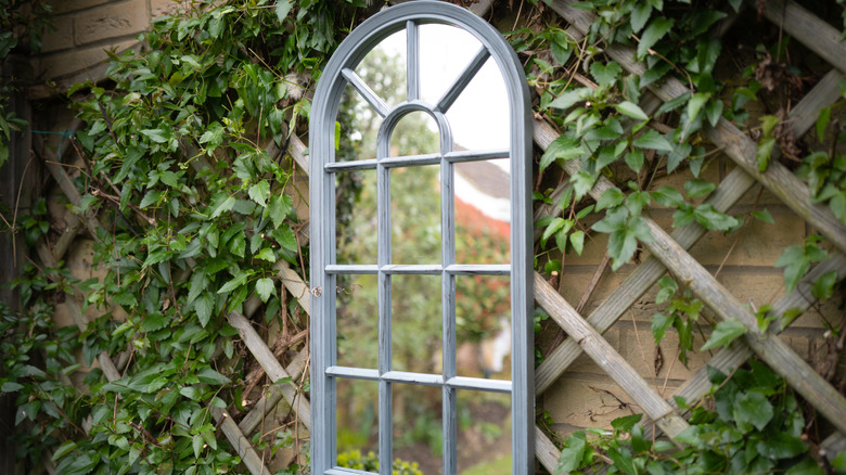 Framed mirror hanging by a garden trellis
