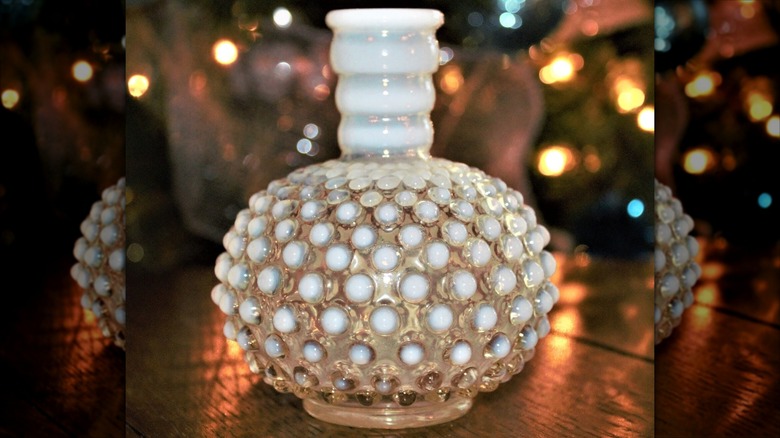 An Anchor Hocking Moonstone Glass perfume bottle sits on a wooden table