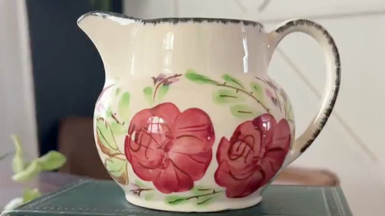 A vintage Blue Ridge Pottery creamer sits on a green book