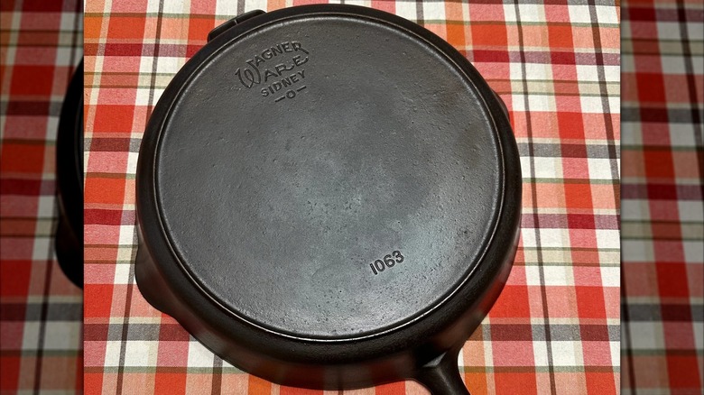 A Wagner Ware cast iron pan sits on a table covered with a plaid cloth