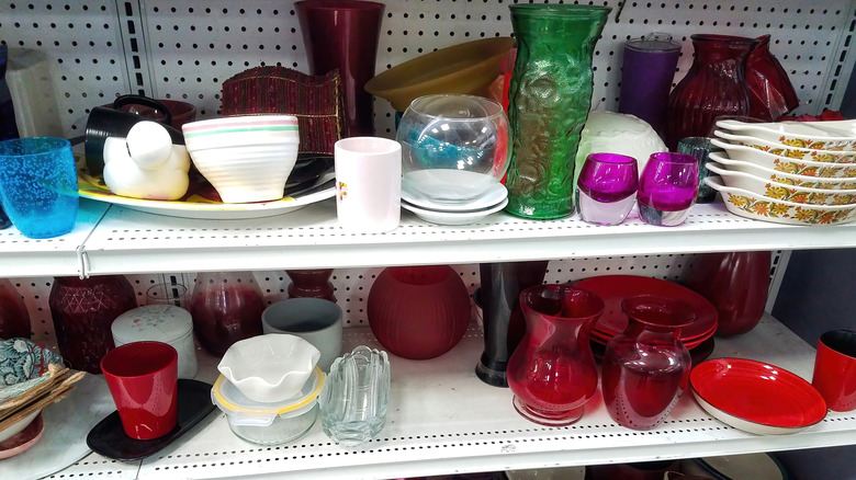 A variety of vintage kitchenware items sit on shelves at a thrift store