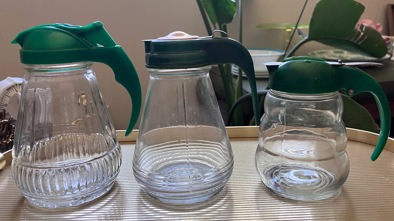 Three vintage maple syrup dispensers have green Bakelite lids