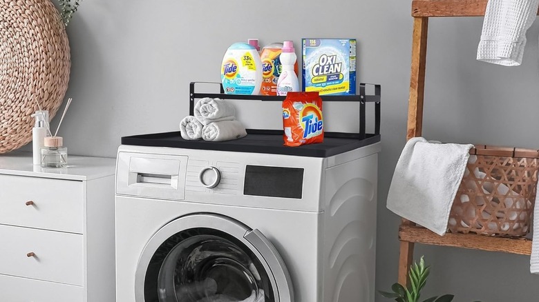 Black dryer countertop with laundry soap on shelves.