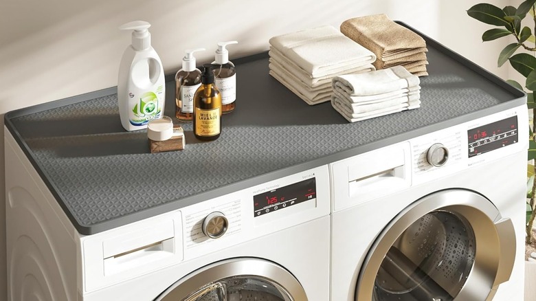 Gray silicon washer and dryer countertop with soaps and towels on it.