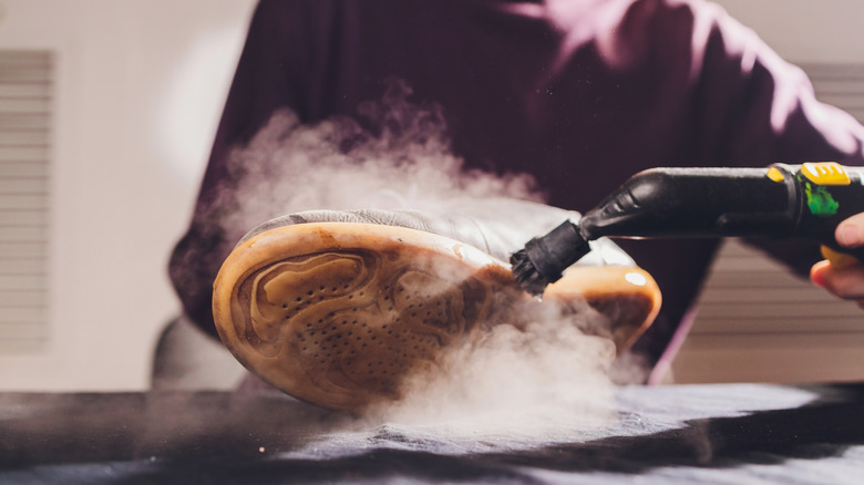 A man using a steamer on a shoe