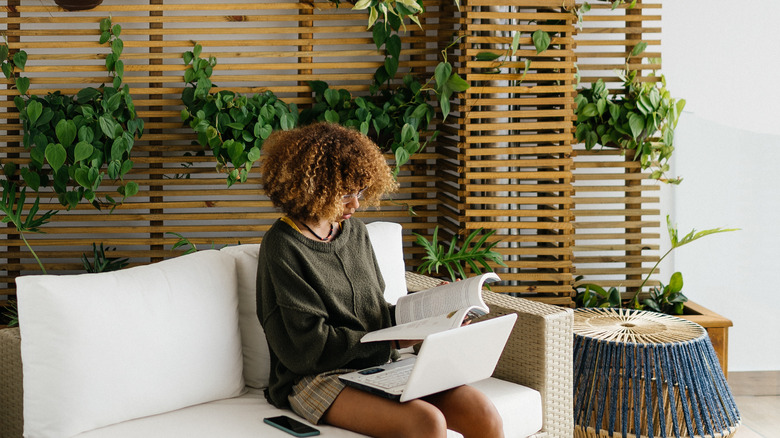 A woman sitting in front of a plant wall.