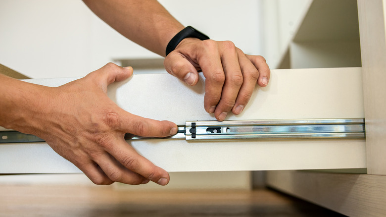 person adjusting tracks of drawer