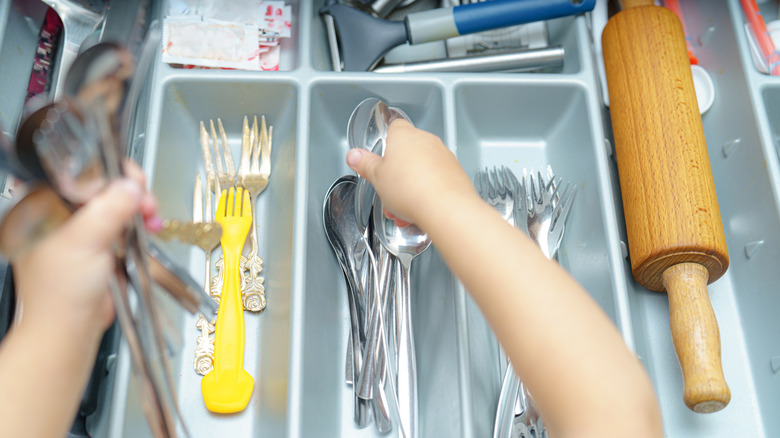 person placing flatware in drawer