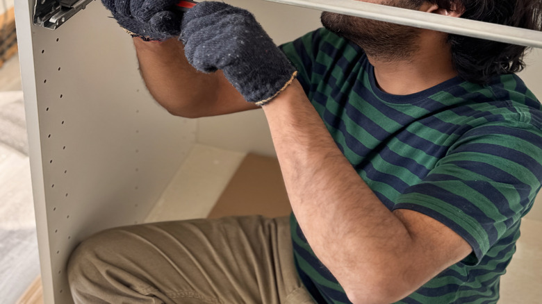 man adding new drawer slide to cabinet