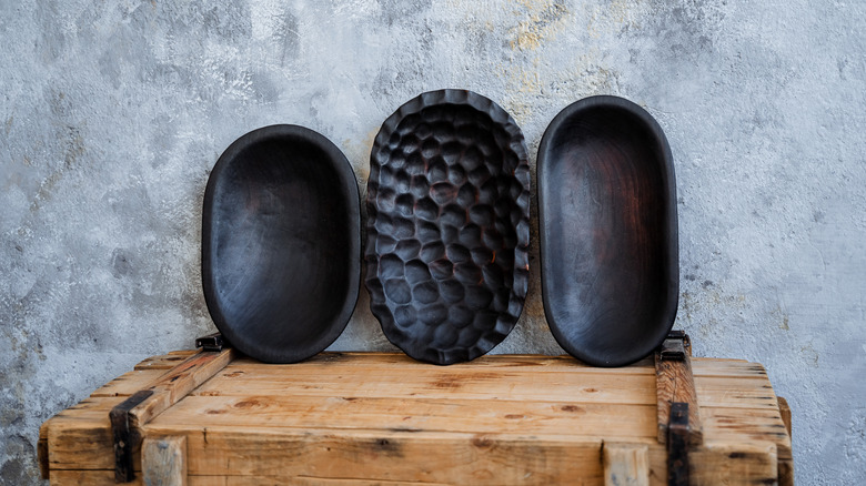 Three dark wood bowls on a wooden chest