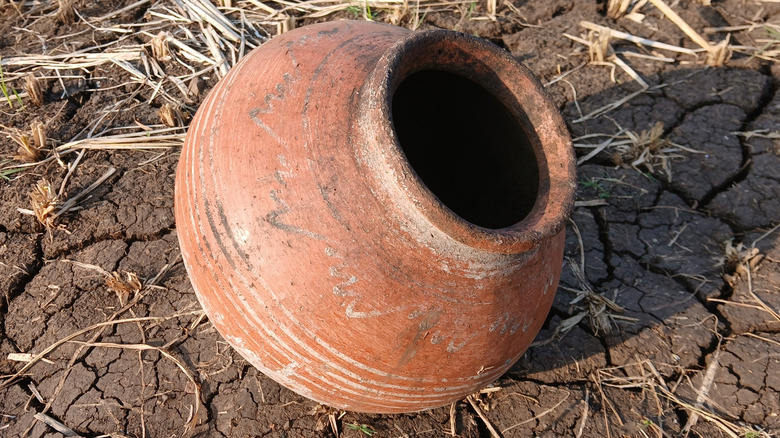 An old clay pot on baked soil.