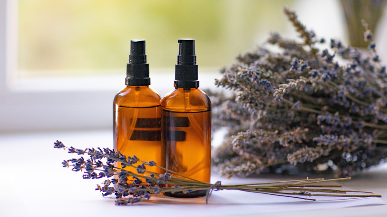 Amber spray bottles contain essential oils with dried lavender sprigs in the background