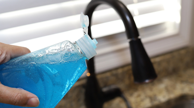 Close-up of a hand holding a bottle of dish soap